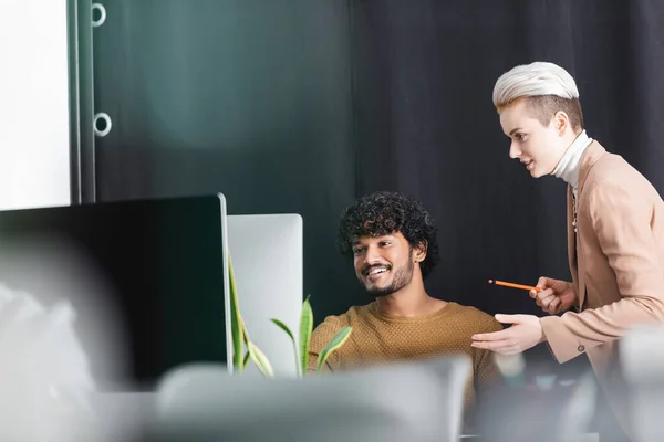 Mujer Rubia Apuntando Monitor Computadora Cerca Del Diseñador Publicidad Indio —  Fotos de Stock