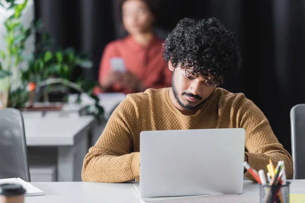 Lockigt Indian Reklam Manager Arbetar Laptop Nära Suddig Afrikansk Amerikansk — Stockfoto