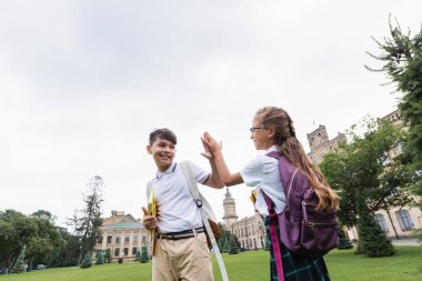 Parkta gülümseyen ırklar arası çocuklar beşlik çakıyor. 