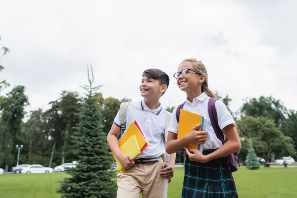 Defterleri açık havaya bakan ırklar arası okul çocukları. 