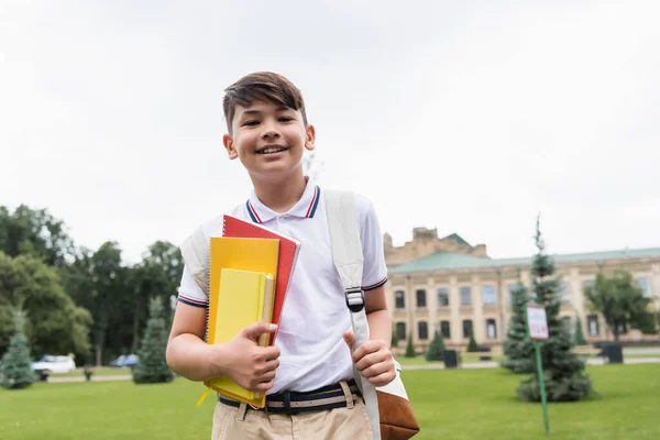 Glada Asiatiska Skolpojke Hålla Kopiera Böcker Och Titta Kameran Utomhus — Stockfoto