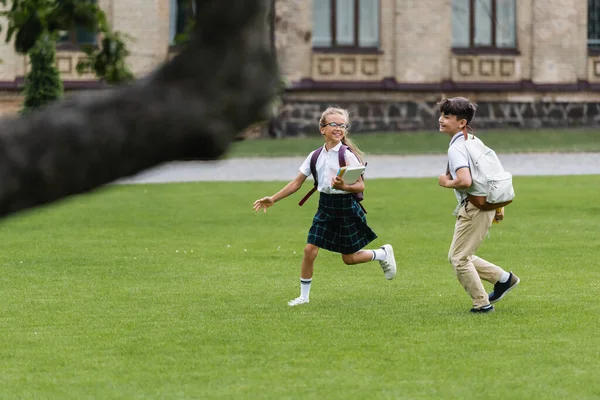 Colegiales Interracial Positivos Con Mochilas Corriendo Césped — Foto de Stock