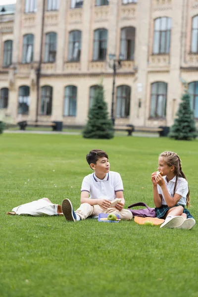 Schoolmeisje Eten Sandwich Buurt Van Aziatische Vriend Lunchboxen Gazon Park — Stockfoto