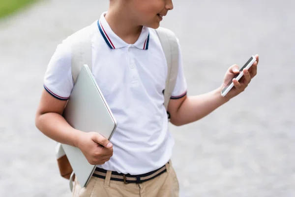スマートフォンやノートパソコンを屋外に保持する学校の少年の作物ビュー — ストック写真