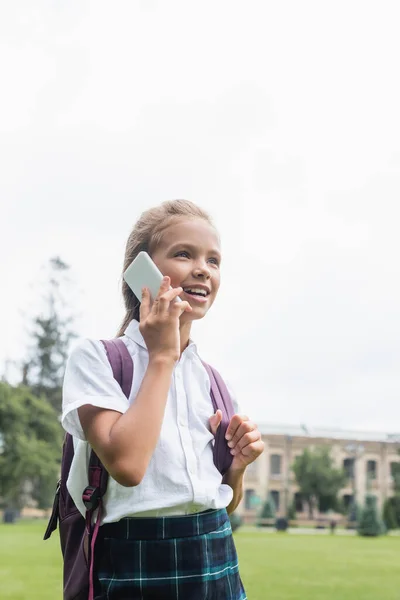 Sırt Çantalı Gülümseyen Okul Çocuğu Dışarıda Cep Telefonuyla Konuşuyor — Stok fotoğraf