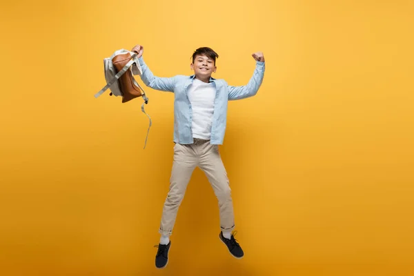 Emocionado Asiático Colegial Celebración Mochila Mostrando Gesto Mientras Saltar Amarillo — Foto de Stock