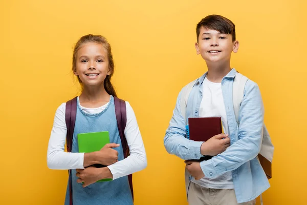 陽気多民族の就学前の子供たちは本を保持し 黄色で隔離されたカメラを見て — ストック写真