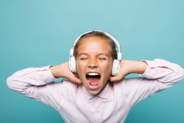 Kızgın liseli kız mavi kulaklıkla müzik dinliyor. 
