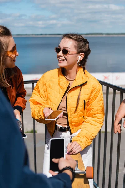 Mujer Sonriente Chaqueta Amarilla Gafas Sol Pie Con Teléfono Inteligente — Foto de Stock