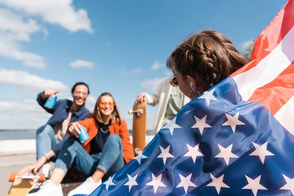 站在户外模糊的多文化朋友身边举着美国国旗的年轻女子 — 图库照片
