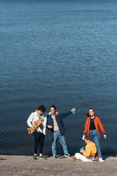 young and trendy multicultural skaters spending time near river 