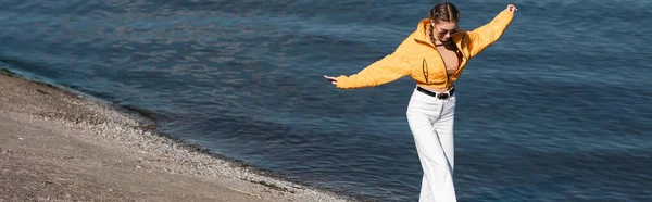 Жінка Жовтій Куртці Йде Витягнутими Руками Вздовж Берега Річки Банер — стокове фото