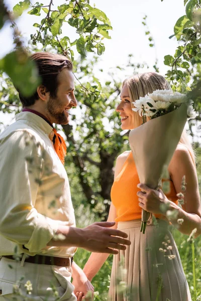 夏の公園で花束を手にスタイリッシュなカップルの笑顔の側面図 — ストック写真