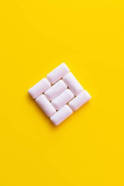 Flat lay of chewing gums in square shape on yellow background  clipart
