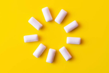 Flat lay of round shape from chewing gums on yellow background  clipart
