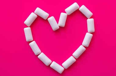 Top view of heart shape from white chewing gums on pink background  clipart