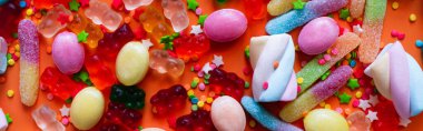 Top view of assorted jelly sweets and candies on orange background, banner  clipart