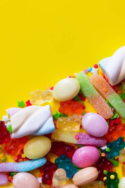 Flat lay with colorful jelly sweets and tasty marshmallows on yellow background  clipart