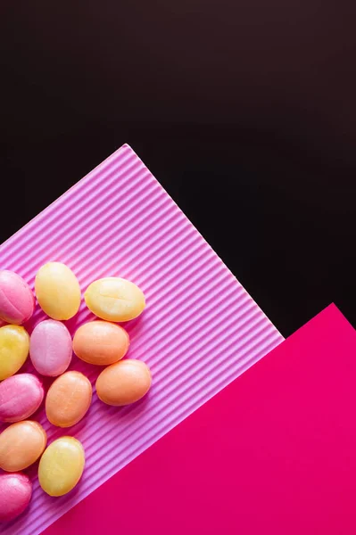 粉色表面上彩色糖果的顶视图 与黑色隔离 — 图库照片