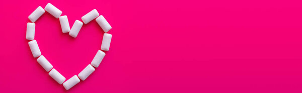 Top view of heart symbol from chewing gums on pink background, banner 