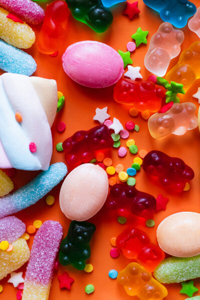 Close up view of colorful sweets and icing decor on orange background 