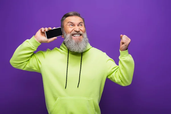 Homem Sênior Espantado Segurando Smartphone Com Tela Branco Isolado Roxo — Fotografia de Stock