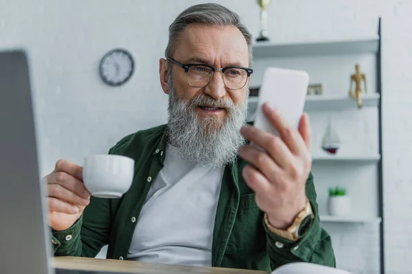 Homme Âgé Barbu Dans Des Lunettes Tenant Tasse Regardant Smartphone — Photo