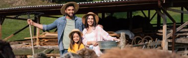 happy family of farmers in straw hats near cattle corral on blurred foreground, banner  clipart