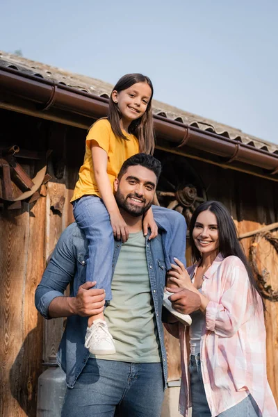 Barbudo Hombre Piggybacking Hija Mirando Cámara Cerca Feliz Esposa Granja — Foto de Stock