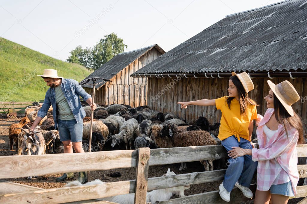happy woman smiling near girl pointing at dad working with cattle in corral 