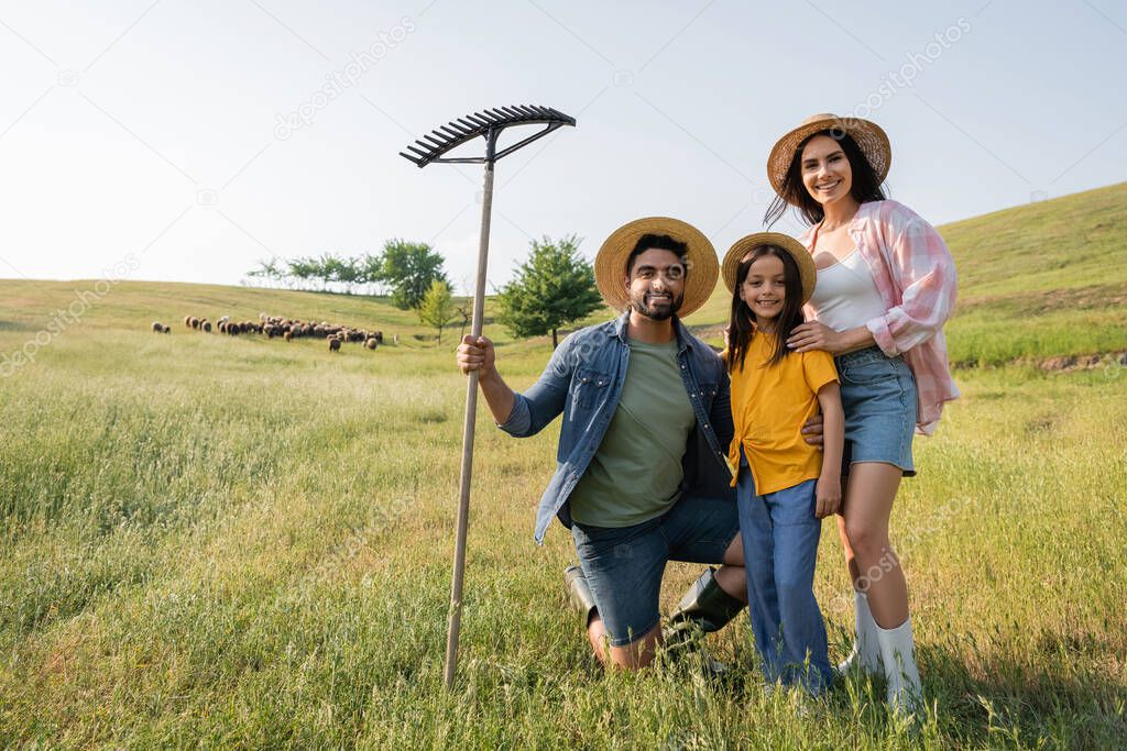 happy farm family looking at camera near herd grazing in scenic meadow