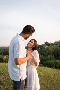 Neşeli bir çift el ele tutuşup dışarıda birbirlerine bakıyorlar.