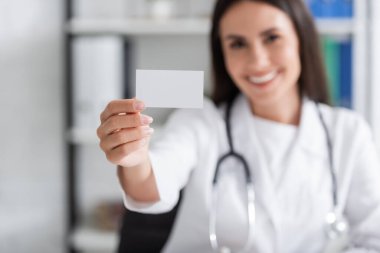 Blurred doctor holding empty business card in clinic 