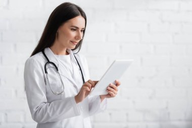 Klinikte dijital tablet kullanan esmer doktor 