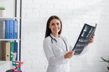 Gülümseyen doktor MRI taraması yapıyor ve klinikteki kameraya bakıyor. 