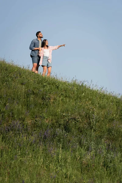 Brunette Woman Pointing Hand While Standing Man Green Hill — Stock Photo, Image