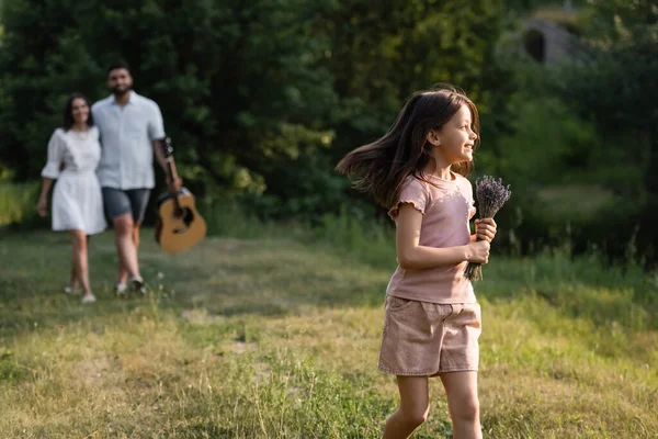 Pleased Girl Flowers Running Countryside Blurred Parents — Stockfoto