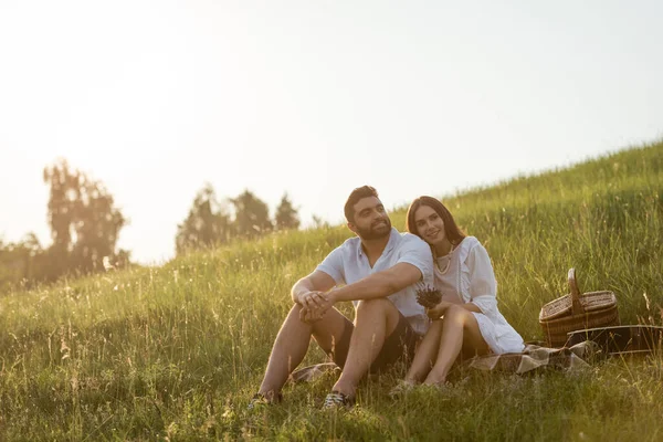 Joyful Couple Sitting Green Slope Wicker Basket Looking Away — Stock Photo, Image