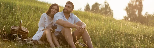 快乐的夫妻坐在乡间的草地上 望着远方 高举横幅 — 图库照片