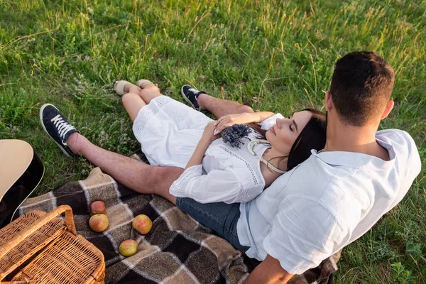 紧闭的眼睛 薰衣草花朵在男朋友和苹果身旁悠闲自在地躺在格子布毯子上的女人 — 图库照片