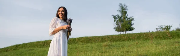 Brunette Woman White Dress Holding Lavender Bouquet Smiling Green Field — Fotografie, imagine de stoc