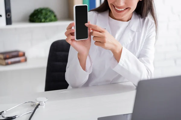 Cropped View Smiling Doctor Pointing Smartphone Video Call Laptop Clinic — Fotografie, imagine de stoc