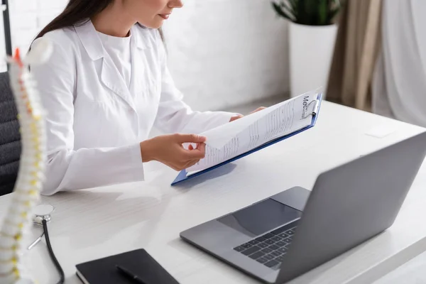 Vista Cortada Médico Segurando Prancheta Perto Laptop Estetoscópio Clínica — Fotografia de Stock