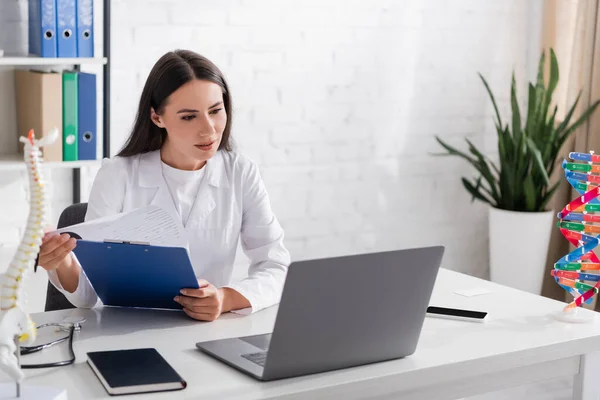 Dokter Memegang Papan Klip Dan Memiliki Video Panggilan Pada Laptop — Stok Foto