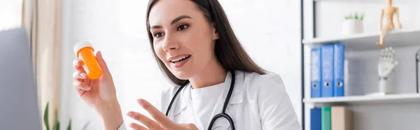 Cheerful Doctor Holding Jar Pills Video Call Laptop Clinic Banner — Stock Photo, Image