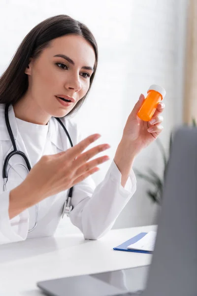 Doctor Holding Pills Gesturing Online Consultation Laptop Clinic —  Fotos de Stock