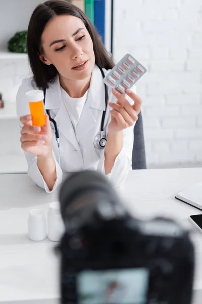 Médico Olhando Para Pílulas Perto Câmera Digital Borrada Clínica — Fotografia de Stock
