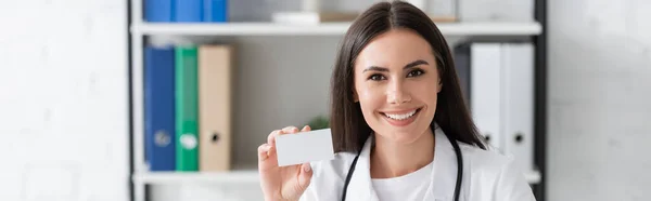 Cheerful Doctor Holding Empty Business Card Hospital Banner — Fotografie, imagine de stoc