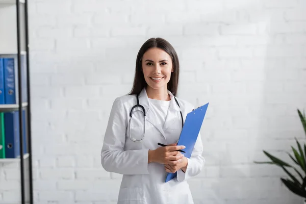 Smiling Doctor Holding Clipboard Looking Camera Hospital — Foto Stock