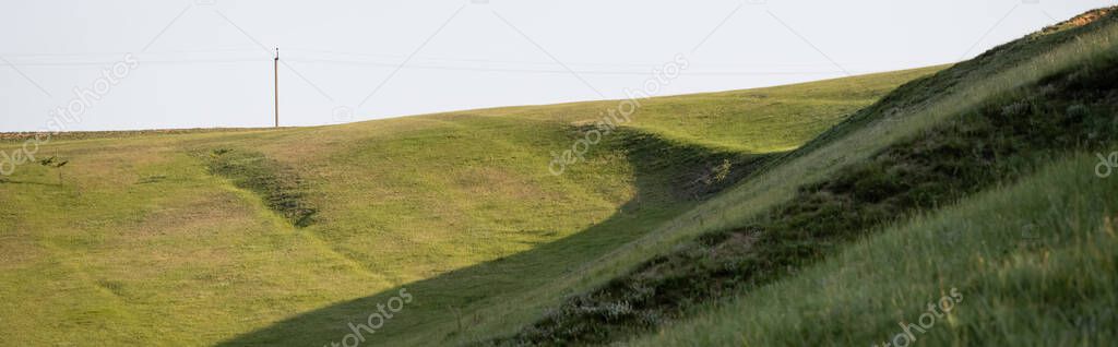 grassy hills under clear sky in countryside, banner